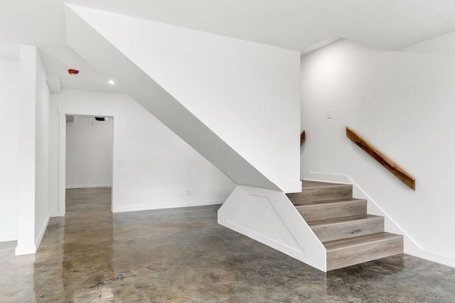 stairs featuring baseboards and concrete floors