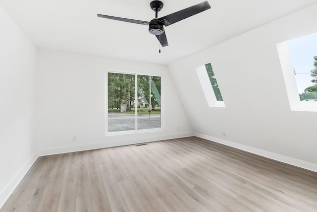 unfurnished room with ceiling fan, baseboards, light wood-style floors, and a skylight