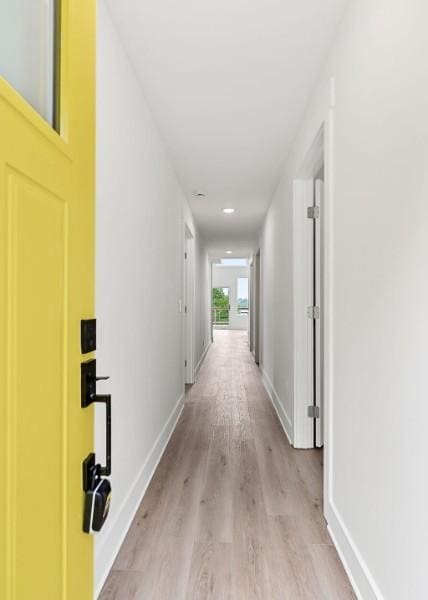 corridor with light wood-style flooring and baseboards