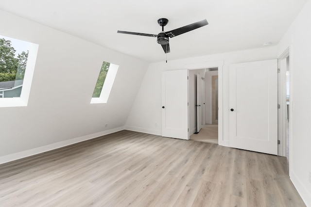 unfurnished bedroom featuring a skylight, light wood-style floors, baseboards, and ceiling fan