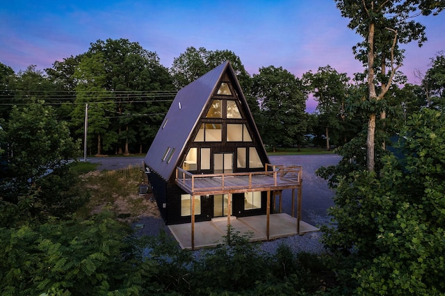 back of house at dusk with a patio area and metal roof