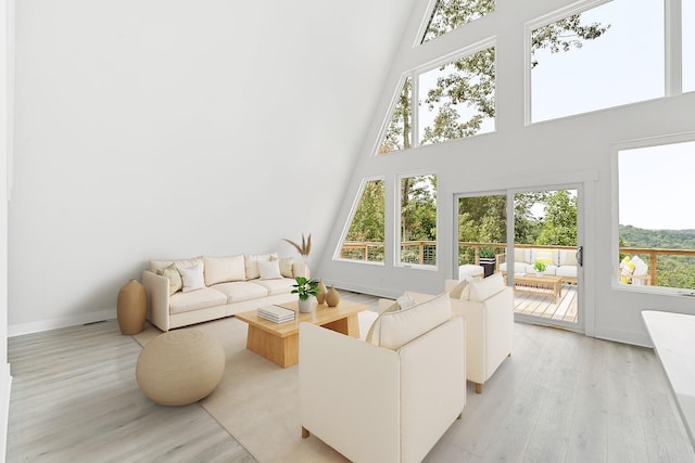 living room featuring baseboards, light wood-style floors, and a towering ceiling