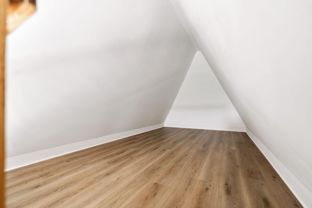 additional living space with vaulted ceiling, baseboards, and wood finished floors