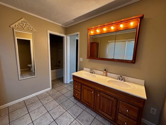 bathroom with double vanity, tile patterned flooring, baseboards, and a sink