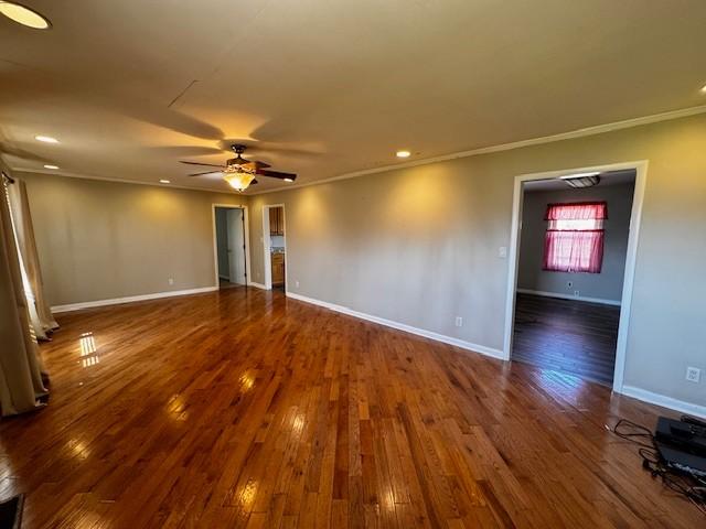 empty room with a ceiling fan, dark wood-style floors, baseboards, recessed lighting, and crown molding