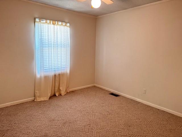 unfurnished room with crown molding, baseboards, ceiling fan, light carpet, and a textured ceiling