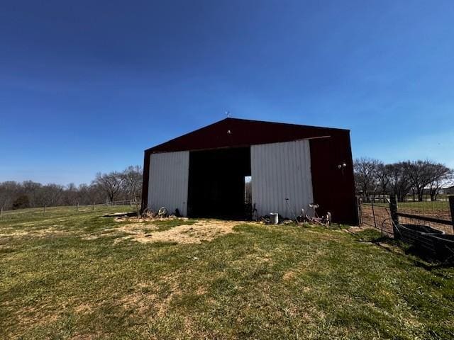 view of pole building featuring a rural view, a lawn, and fence