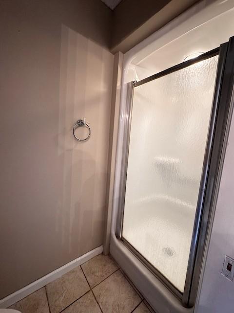 full bathroom featuring tile patterned floors, a shower stall, and baseboards