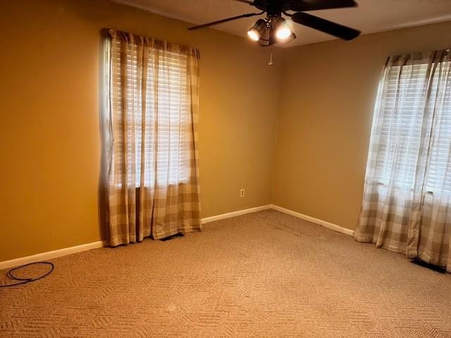 unfurnished room featuring plenty of natural light, baseboards, a ceiling fan, and carpet floors