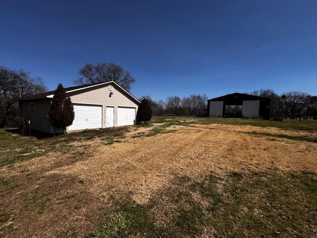 view of yard with driveway, an outdoor structure, and a garage