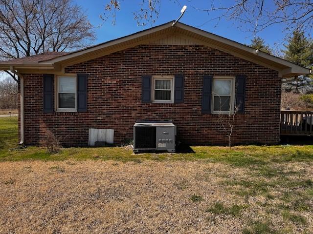 view of property exterior with brick siding, central air condition unit, and a lawn