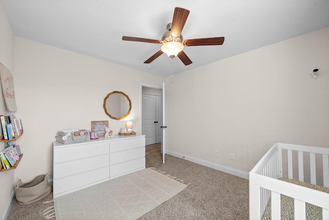 bedroom featuring baseboards, a crib, ceiling fan, and carpet flooring