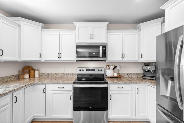 kitchen with light stone counters, appliances with stainless steel finishes, and white cabinetry