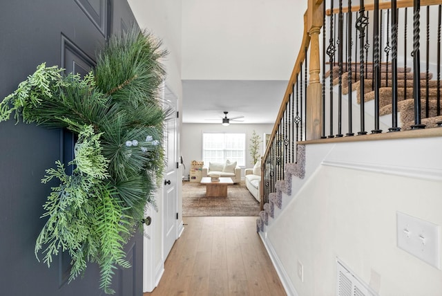 foyer featuring visible vents, light wood-style flooring, stairs, and a ceiling fan