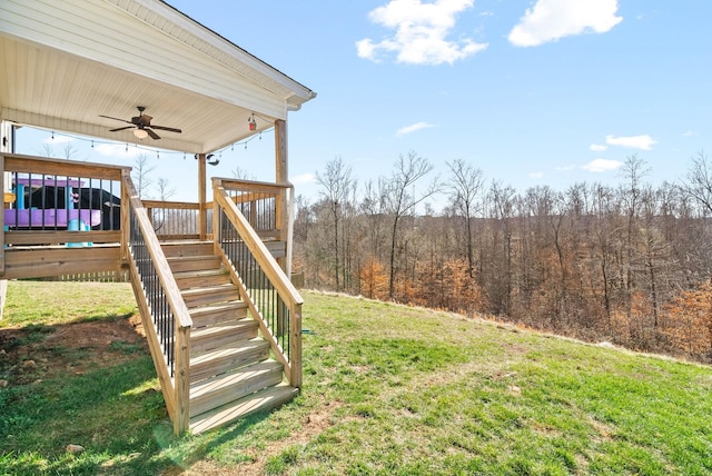 view of yard featuring stairway, a view of trees, a wooden deck, and a ceiling fan