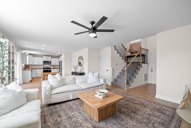 living room featuring baseboards, stairs, light wood-type flooring, recessed lighting, and a ceiling fan