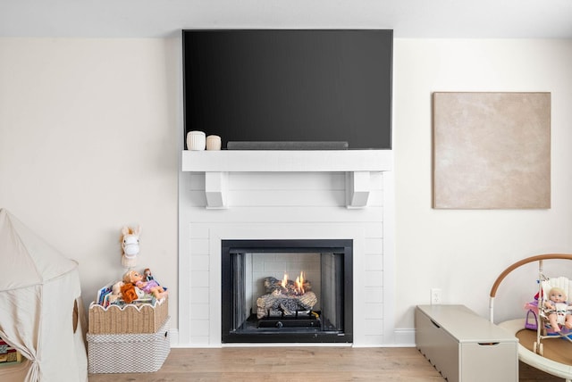 interior details featuring baseboards, a lit fireplace, and wood finished floors