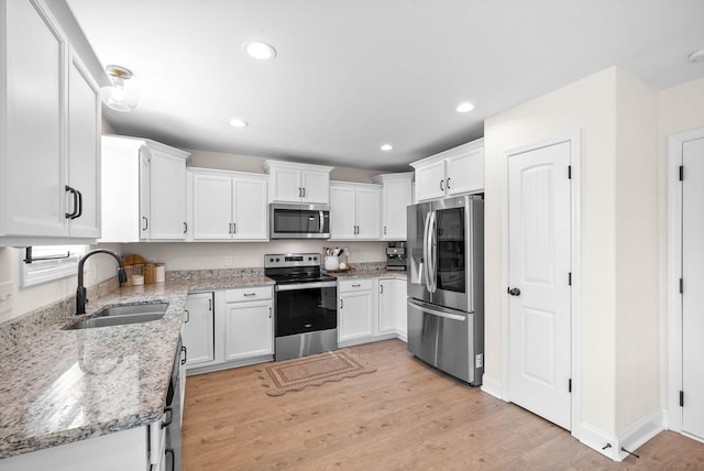 kitchen featuring a sink, stainless steel appliances, light wood finished floors, and white cabinetry