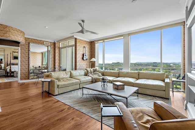 living room featuring a wealth of natural light, light wood-type flooring, ceiling fan, and crown molding