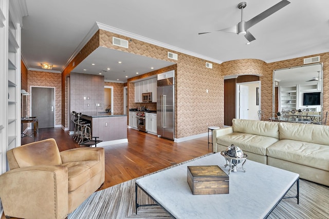 living room with visible vents, dark wood-style floors, a ceiling fan, and ornamental molding