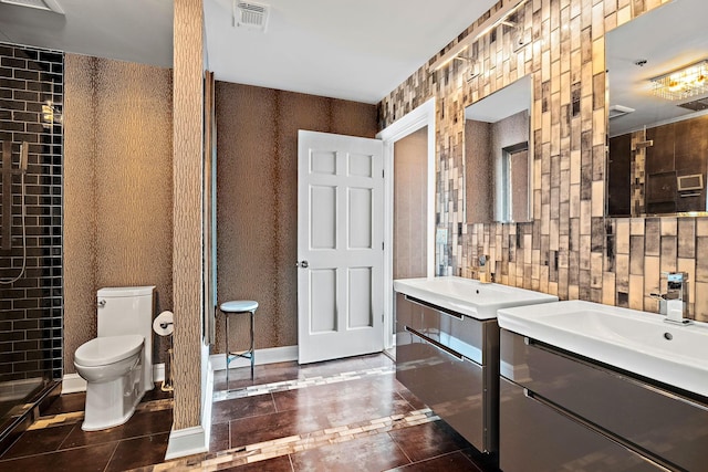 bathroom featuring visible vents, baseboards, toilet, two vanities, and a sink