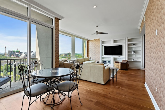 dining area featuring built in shelves, wood finished floors, baseboards, brick wall, and ceiling fan