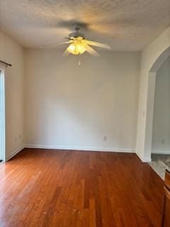 spare room with ceiling fan, arched walkways, a textured ceiling, and wood finished floors