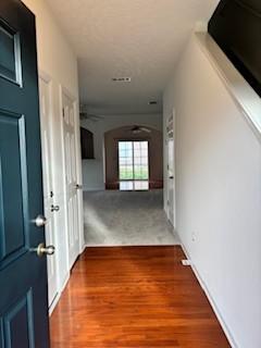 hall with arched walkways and wood finished floors