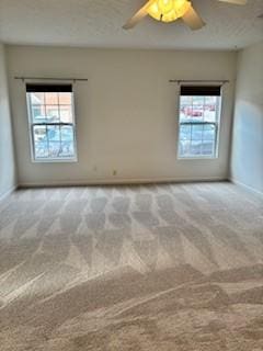 unfurnished room with a wealth of natural light, baseboards, carpet floors, and a ceiling fan