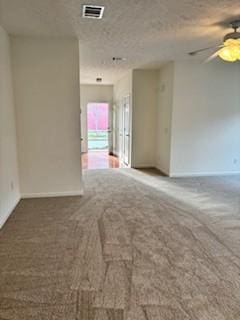 unfurnished room with a ceiling fan, baseboards, carpet, visible vents, and a textured ceiling