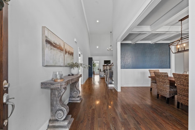 foyer featuring wood finished floors, coffered ceiling, wainscoting, beamed ceiling, and a decorative wall