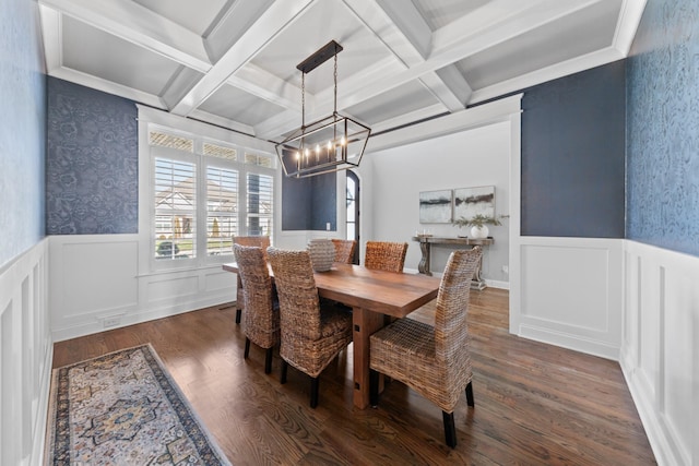 dining space with beam ceiling, a wainscoted wall, an inviting chandelier, and dark wood-style flooring