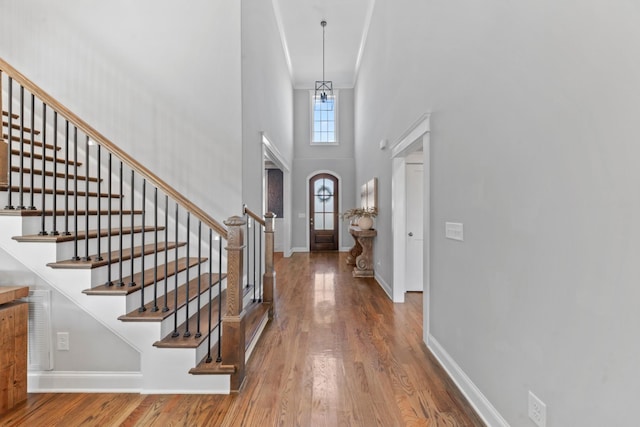 foyer entrance with stairway, baseboards, and wood finished floors