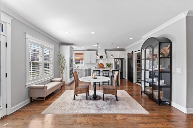 dining room featuring ornamental molding, baseboards, a barn door, and dark wood-style flooring