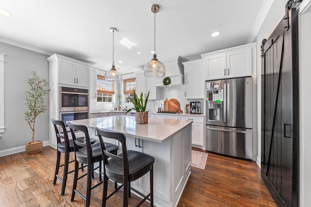 kitchen featuring dark wood finished floors, light countertops, white cabinets, appliances with stainless steel finishes, and a barn door