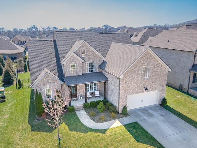 traditional-style house with a garage, a front yard, concrete driveway, and brick siding