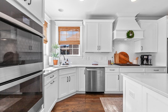 kitchen featuring backsplash, light countertops, stainless steel appliances, white cabinetry, and a sink