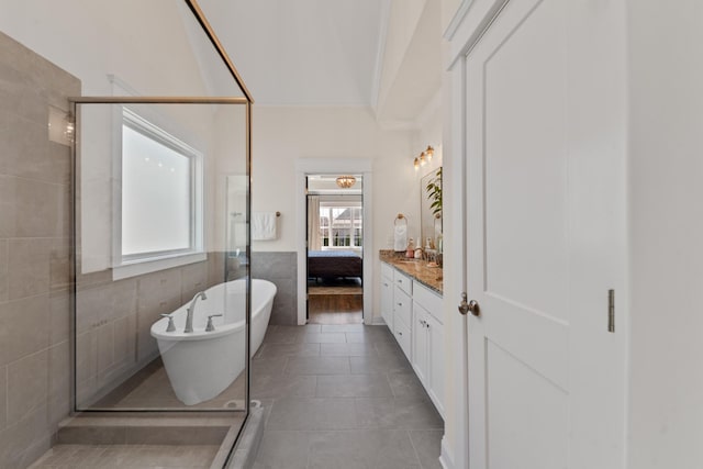 ensuite bathroom featuring tile patterned flooring, tile walls, a stall shower, a soaking tub, and vanity