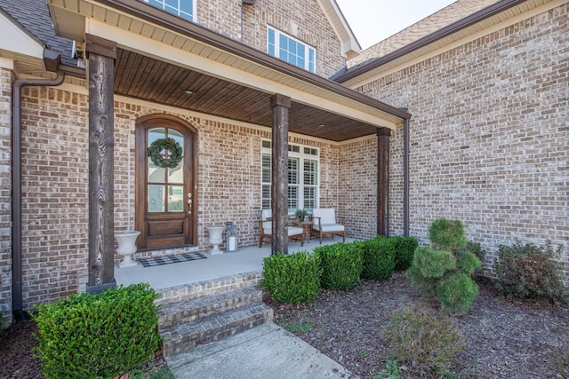 doorway to property with brick siding and covered porch