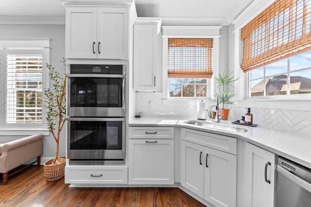 kitchen featuring a sink, white cabinetry, appliances with stainless steel finishes, crown molding, and dark wood-style flooring