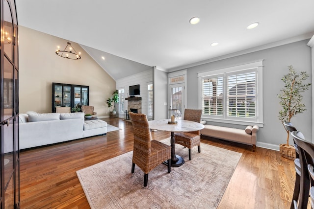 dining area featuring baseboards, lofted ceiling, recessed lighting, a fireplace, and wood-type flooring