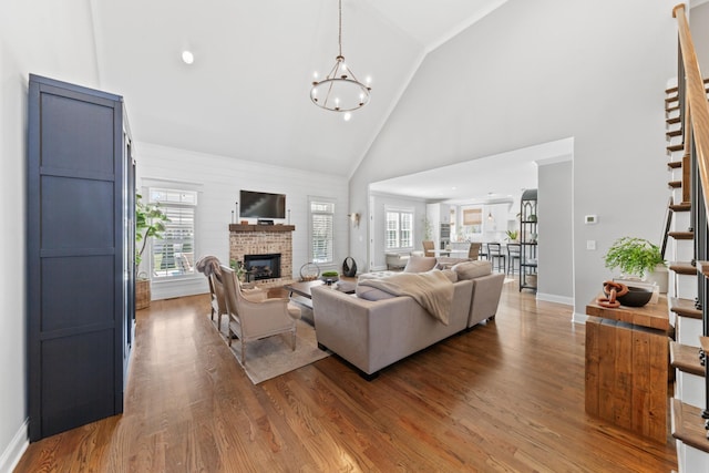 living room featuring stairway, a brick fireplace, wood finished floors, and a wealth of natural light