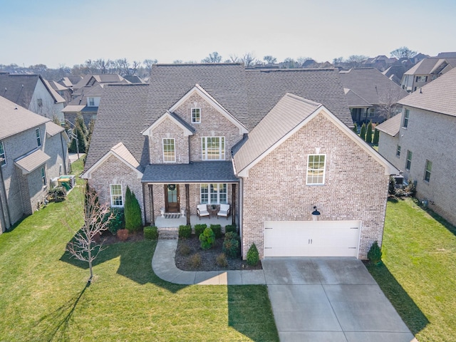 traditional home with brick siding, driveway, a front yard, and a garage