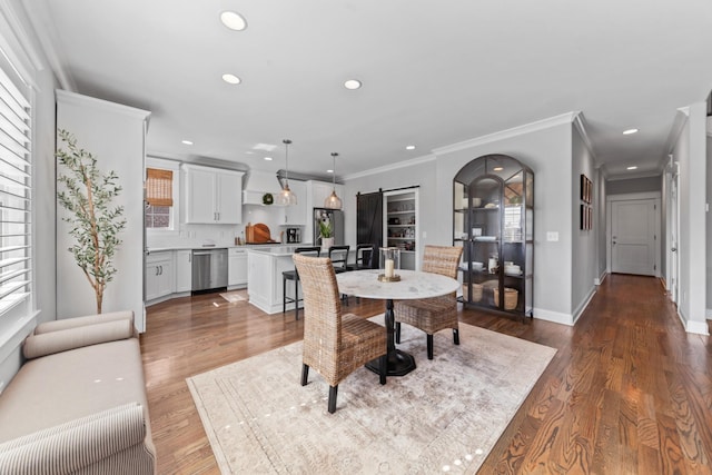 dining space with ornamental molding, wood finished floors, recessed lighting, arched walkways, and baseboards