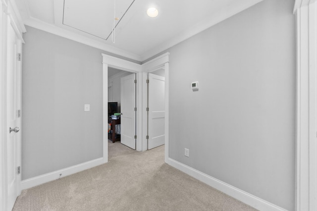 unfurnished room with light colored carpet, attic access, and baseboards