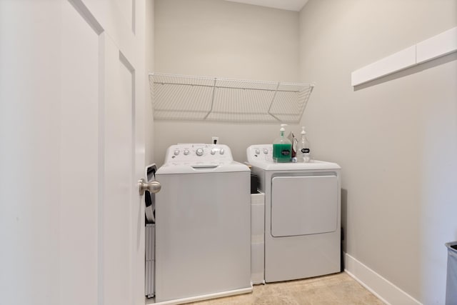 clothes washing area featuring washer and clothes dryer, laundry area, and baseboards