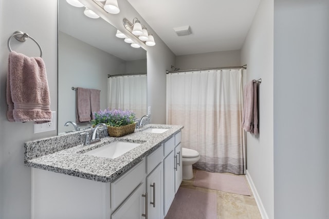 bathroom with double vanity, toilet, baseboards, and a sink