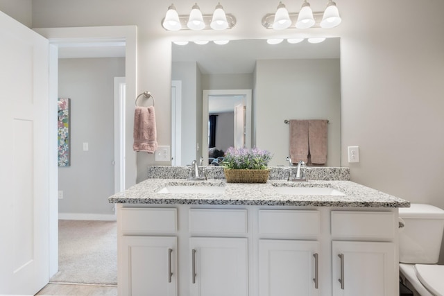 full bathroom with a sink, baseboards, toilet, and double vanity