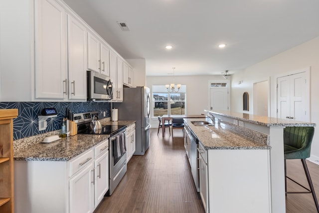 kitchen with visible vents, a sink, stainless steel appliances, white cabinets, and a kitchen breakfast bar