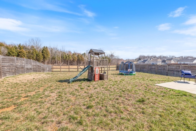 view of yard featuring a trampoline, a fenced backyard, and a playground